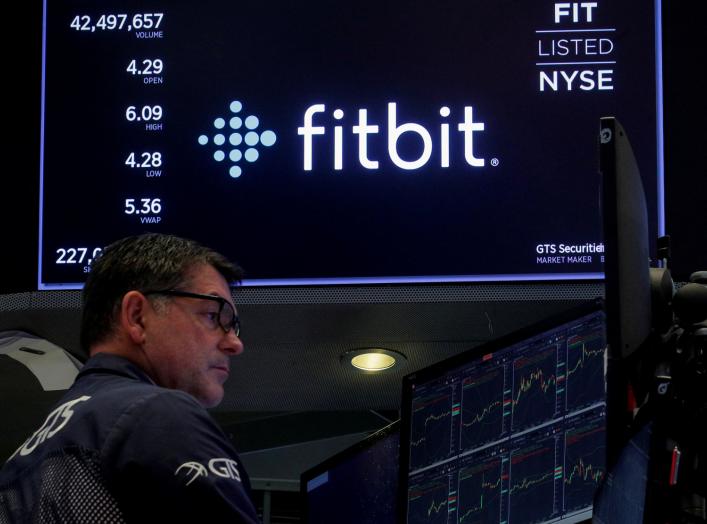 A trader works at his post as the logo for wearable device maker Fitbit Inc. is displayed on a screen on the floor of the New York Stock Exchange (NYSE) as begins public trading in New York, U.S., October 28, 2019. REUTERS/Brendan McDermid