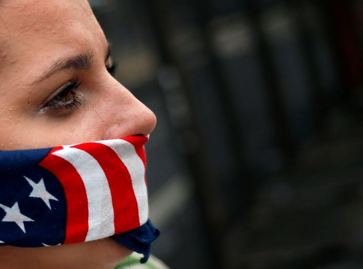 A supporter of U.S. Senator Bernie Sanders covers her mouth with a bandana in the colors of the American flag while standing along the perimeter fence of the 2016 Democratic National Convention in Philadelphia, Pennsylvania on July 28, 2016. REUTERS/Adree