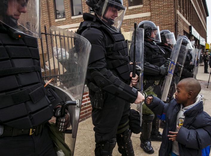 A young boy greets police officers in riot gear during a march in Baltimore, Maryland May 1, 2015 following the decision to charge six Baltimore police officers -- including one with murder -- in the death of Freddie Gray, a black man who was arrested and