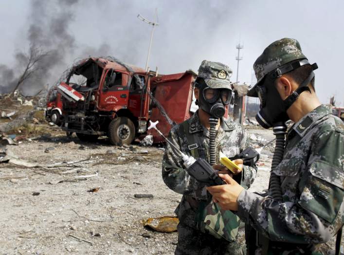 Soldiers of the People's Liberation Army anti-chemical warfare corps work next to a damaged firefighting vehicle at the site of Wednesday night's explosions at Binhai new district in Tianjin, China, August 16, 2015.