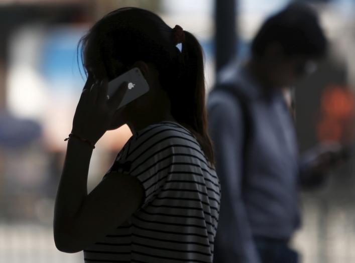 A woman speaks on her iPhone as she walks on a busy street in downtown Shanghai September 10, 2013. REUTERS/Aly Song/File Photo