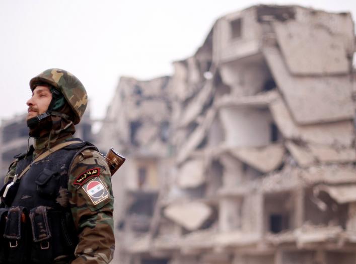 A member of forces loyal to Syria's President Bashar al-Assad stands near damaged buildings in Aleppo's Salaheddine district, Syria December 16, 2016. REUTERS/Omar Sanadiki