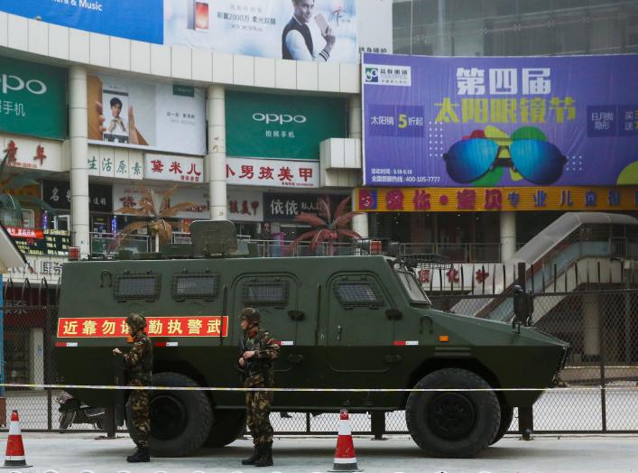 Security personel stand in front of an armoured vehicle in Kashgar, Xinjiang Uighur Autonomous Region, China, March 24, 2017. REUTERS/Thomas Peter