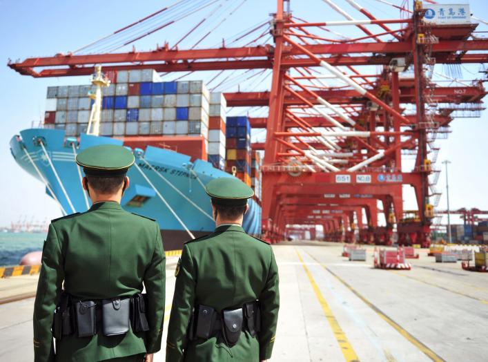 Police officers are seen in front of a cargo ship with containers at a port in Qingdao, Shandong province, China April 6, 2018. REUTERS/Stringer