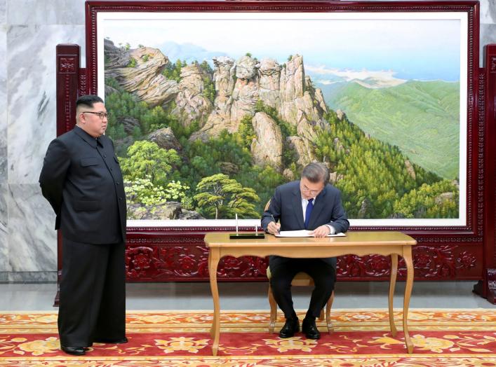 South Korean President Moon Jae-in signs a guestbook as North Korean leader Kim Jong Un looks on before their summit at the truce village of Panmunjom, North Korea, in this handout picture provided by the Presidential Blue House on May 26, 2018. Picture t