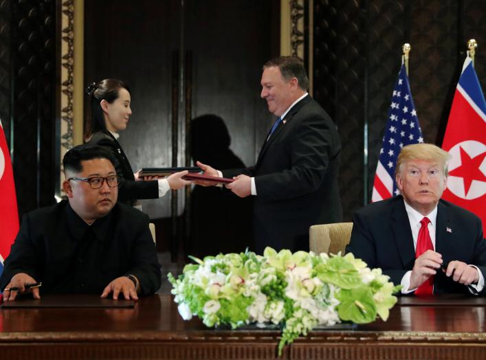 North Korea's leader Kim Jong Un looks at U.S. President Donald Trump as Kim's sister Kim Yo Jong exchanges document with U.S. Secretary of State Mike Pompeo at their summit at the Capella Hotel on Sentosa island in Singapore June 12, 2018. REUTERS/Jonath