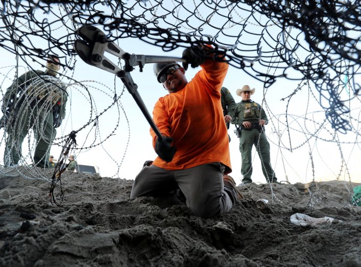 A worker on the U.S. side installs concertina wire along the border wall with the United States as seen from Tijuana, Mexico, December 11, 2018. REUTERS/Mohammed Salem