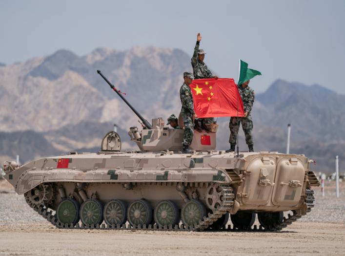 Chinese soldiers of People's Liberation Army (PLA) pose for photos with a Chinese national flag on a tank during the Suvorov Attack contest of the International Army Games 2019 in Korla, Xinjiang Uighur Autonomous Region, China August 4, 2019. Reuters