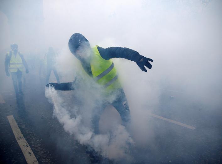 FILE PHOTO: Tear gas fills the air as a protester wearing a yellow vest, a symbol of a French drivers' protest against higher diesel taxes, demonstrates near the Place de l'Etoile in Paris, France, December 1, 2018. REUTERS/Stephane Mahe/File Photo