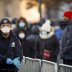 A New York City Police officer (NYPD) puts on gloves as people wait in line to be tested for coronavirus disease (COVID-19), outside Elmhurst Hospital Center in the Queens borough of New York City, U.S., March 26, 2020. REUTERS/Stefan Jeremiah